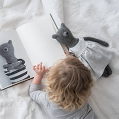 Thumbnail image of a little girl reading a book featuring an image of a bear.