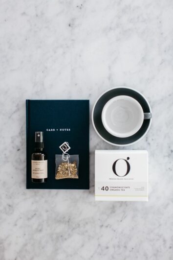 An image of The Grace Files Calm Kindness Kit showing the Care + Notes journal, tea cup, calming mist and organic tea. A perfect get well care package.