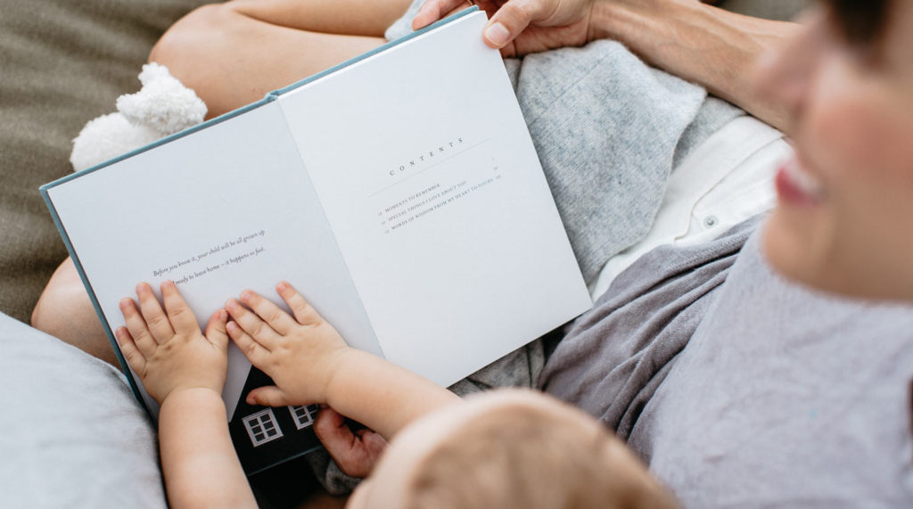 Image of a mother reading to her young child from The Grace Files Love + Notes journal. Part of a blog article detailing how you can write a love letter to your child.