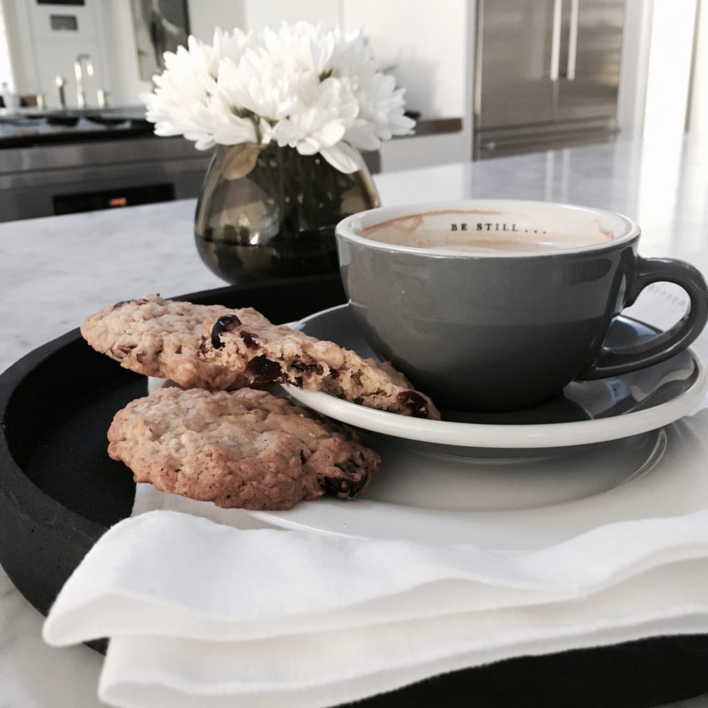 Image of a cup of tea with biscuits on a marble table.